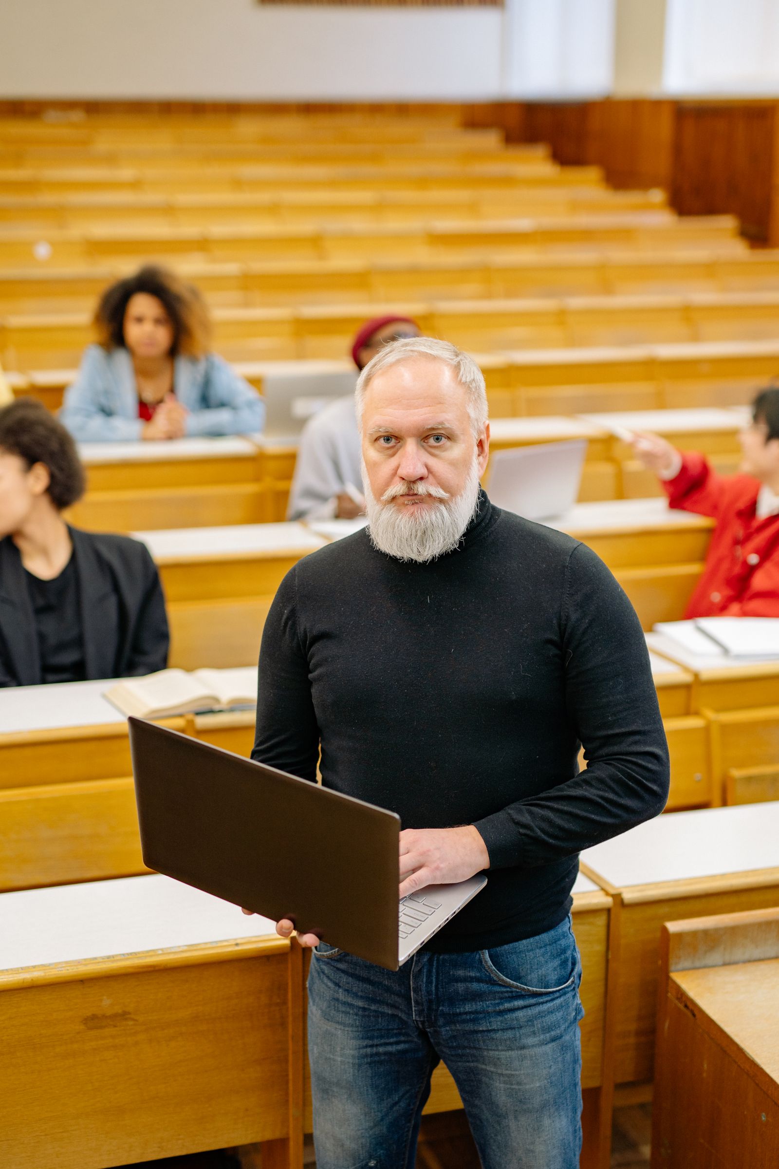 Senior professor working on a laptop in a lecture theatre