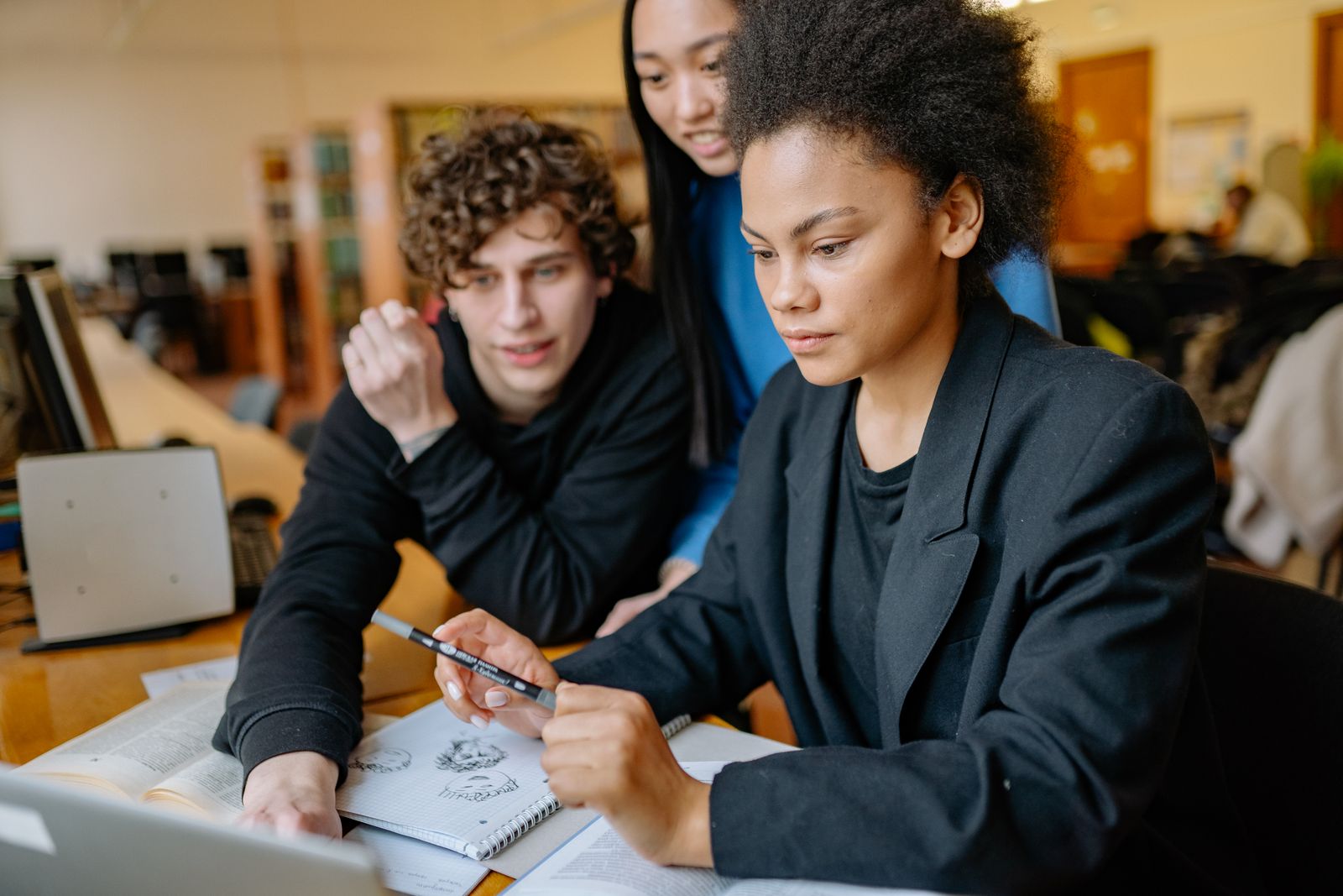 Students collaborating around a table with a tablet and a laptop