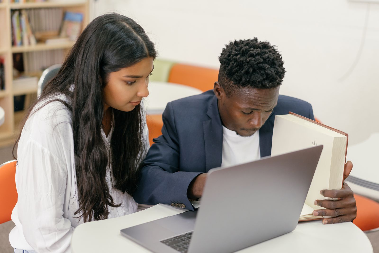 Students working together around a table with a tablet and a laptop